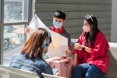 Asian young couple with face mask check map together at departure waiting area at airport terminal