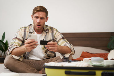 Portrait of young man using mobile phone while sitting on table