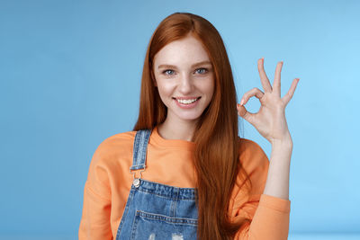 Portrait of smiling young woman against blue background