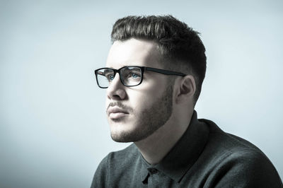 Young man wearing eyeglasses against white background