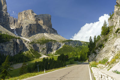 Road amidst trees and mountains against sky