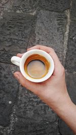 Cropped hand holding coffee cup over street