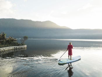 A female paddleboarding on a lake at sunrise