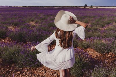 Rear view of woman wearing hat while standing at farm