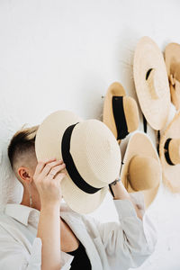 Hipster modern woman and many straw hats like interior decorate the walls in apartment