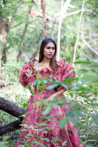 Portrait of woman standing by pink flower