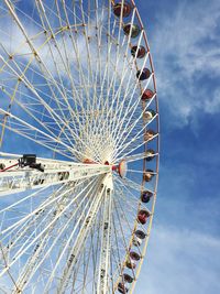 Low angle view of ferris wheel against cloudy sky