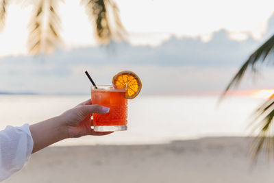 Close-up of hand holding drink at beach