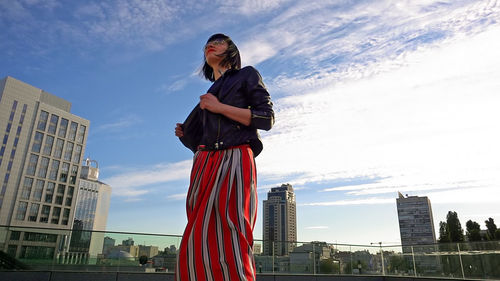 Low angle view of woman standing in city against sky