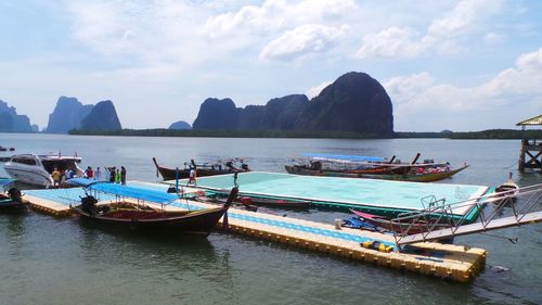 Boats in sea against cloudy sky