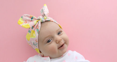 Newborn baby girl smiling pink background