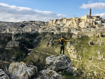 Man standing on rock against sky