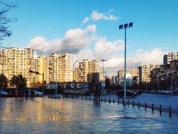 Road by buildings against sky in city