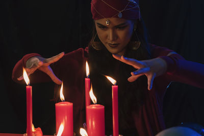 Female fortune teller with burning candles at home