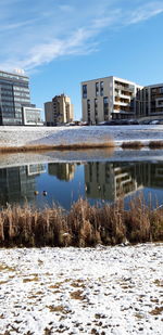 Buildings by lake against sky in city