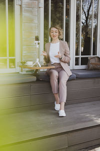 Portrait of a smiling young woman sitting on window