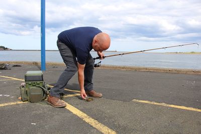 Side view of man standing by sea against sky