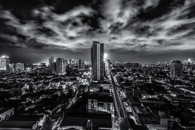 Illuminated cityscape against cloudy sky