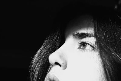 Close-up of thoughtful young woman against black background