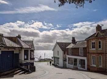 Houses by sea against sky