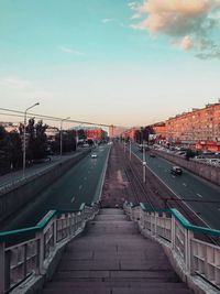 Bridge over road in city against sky during sunset