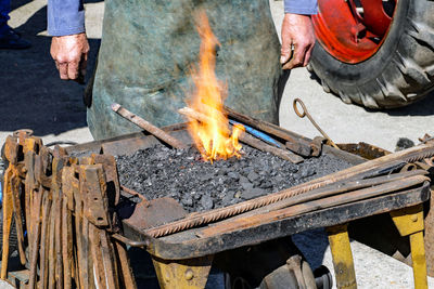 Midsection of man heating metal in workshop