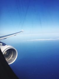 Close-up of airplane flying over sea against clear blue sky