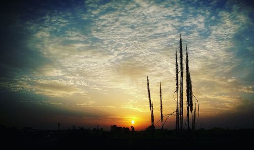 Silhouette of electricity pylon against sky during sunset