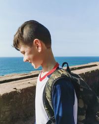 Boy looking at beach against sky