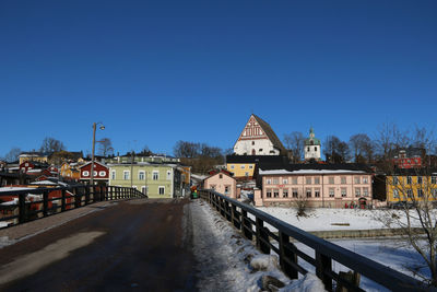 Street amidst buildings against clear blue sky