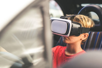 Close-up of boy wearing virtual reality simulator while sitting in car