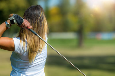 Woman playing golf, swing, rear view