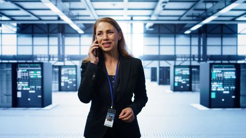 Businesswoman talking on mobile phone while standing in cafe
