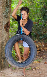 Portrait of young woman standing by tree trunk