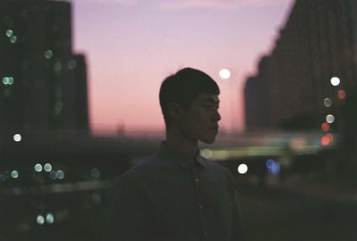 Man standing in illuminated city against sky at night