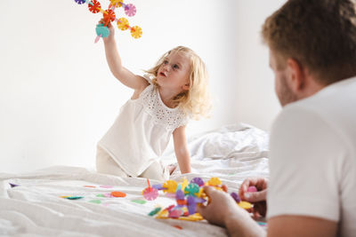 Happy cute caucasian toddler, girl playing with adult, man with colourful toy circles.fathers day