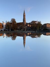 Reflection of building in lake against clear blue sky