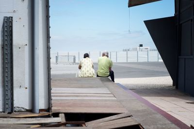 Rear view of couple sitting with sky in background