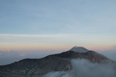 Scenic view of volcanic mountain against sky during sunset