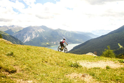 Man riding bicycle on mountain against sky