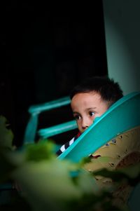 Boy looking away while sitting on bench