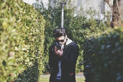 Man photographing amidst plants at park
