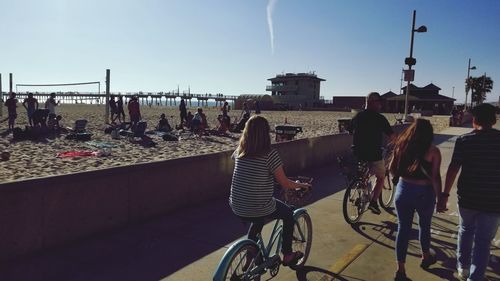 People on bicycle in city against sky