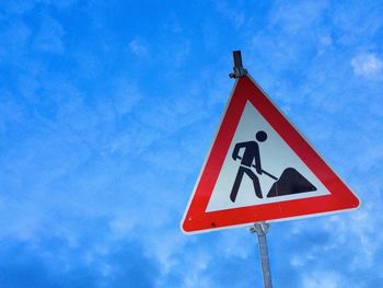 Low angle view of road sign against blue sky