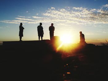 Silhouette of people standing on landscape at sunset