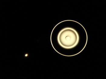 Low angle view of illuminated lighting equipment against black background