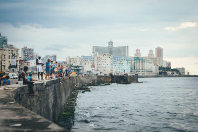 Sea by buildings against sky in city