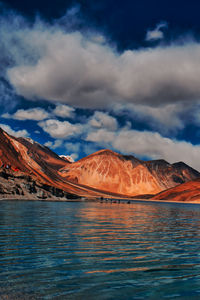 Scenic view of lake by mountains against sky