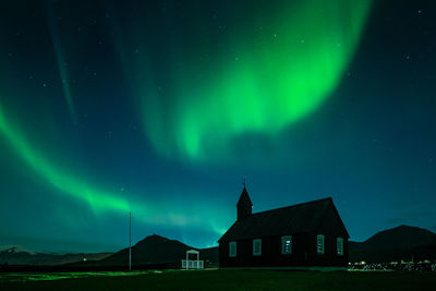 Church on field against aurora borealis at night