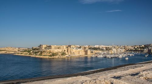 Scenic view of sea by buildings against blue sky